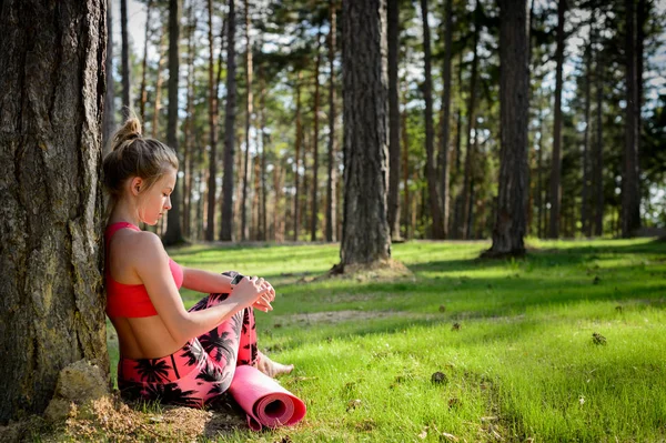Jonge aantrekkelijke vrouw nemen van een pauze na yoga training en toetsing van haar slimme horloge. Sport, fitness, training concept — Stockfoto
