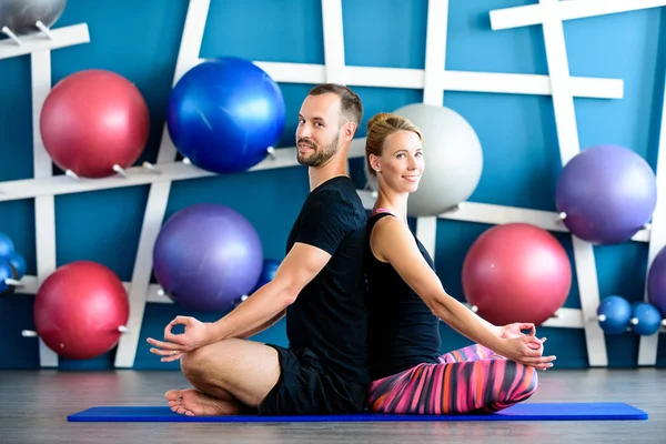 Genç gülümseyen çift bir stüdyoda Yoga yapıyor. Yoga sınıfındaki lotus pozisyonu genç insanlar. Yoga grup kavramı — Stok fotoğraf