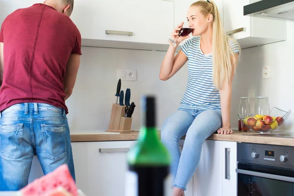 Çekici genç beyaz adam yemekleri mutfak tezgahına oturmuş kız arkadaşı süre kadar yıkama kırmızı şarap tutar