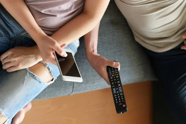 Unga oigenkännliga par hemma, tittar på TV och textning — Stockfoto