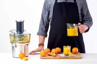 Modern elektrikli meyve sıkacağı, sağlıklı yaşam Detoks kavramı beyaz arka plan üzerinde kullanılarak portakal suyu, taze hazırlanıyor bir önlük giyen anonim adam yapılan