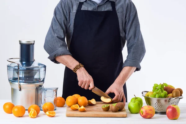 Anonym man bär ett förkläde, förbereda färsk fruktjuice med hjälp av moderna elektriska juicepressen, hälsosam livsstil detox koncept på vit bakgrund — Stockfoto