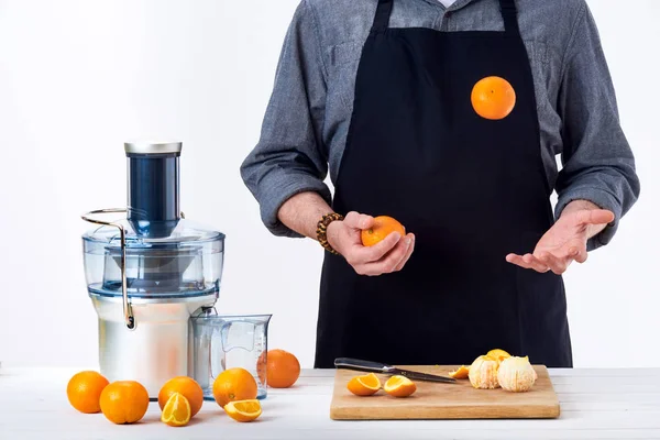 익명의 남자는 앞치마를 입고 갓 준비 만든 오렌지 주스, 현대 전기 과즙 기, 흰색 바탕에 건강 한 라이프 스타일 해독 개념을 사용 하 여 — 스톡 사진