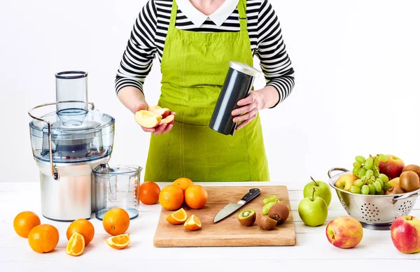 Анонімна жінка в фартусі, готує свіжий фруктовий сік з використанням сучасного електричного соку, концепція детоксикації здорового способу життя на білому тлі — стокове фото