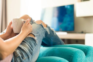 TV izlerken, kahve zevk güzel genç kadın evde kanepede rahatlatıcı