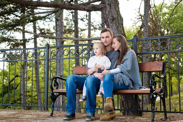 Üç birlikte onların vaktinizi bir parkta bir bankta oturmuş mutlu aile. — Stok fotoğraf