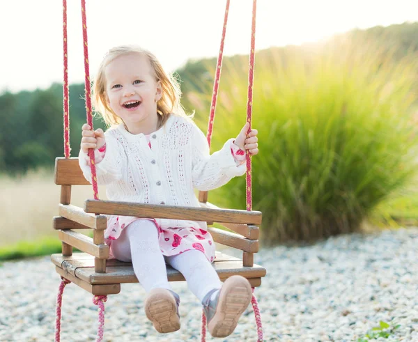 Uma menina a balançar num parque infantil. Infância, Liberdade, Feliz, Conceito de Verão ao ar livre — Fotografia de Stock