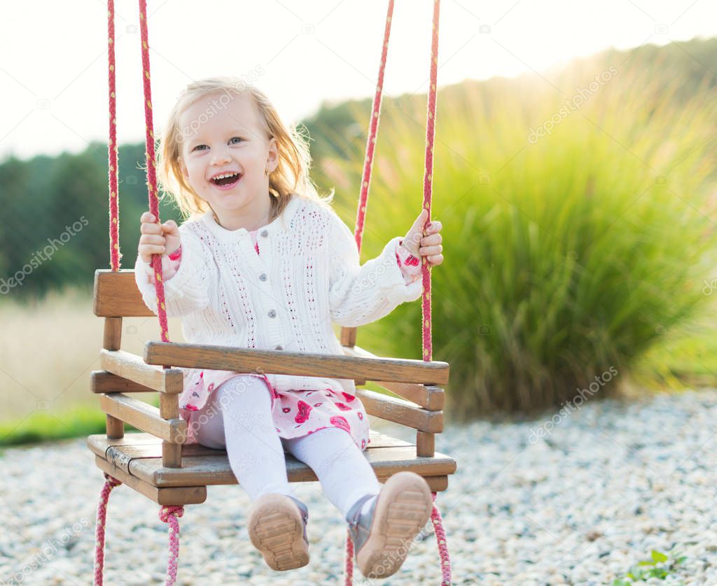 Little girl swinging on a playground. Childhood, Freedom, Happy, Summer Outdoor Concept