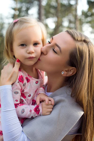 Unga ensamstående mamma hålla söt småbarn flicka dotter i famnen och ger henne en kyss på en kind — Stockfoto