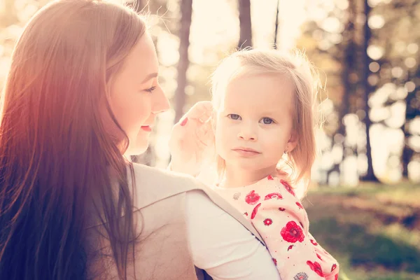 Young single mother holding cute toddler girl daughter in her arms and stroking her hair, girl power concept, daughter looking into the camera — Stock Photo, Image