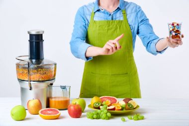 Sağlıklı yaşam detoks diyet kavramı. Meyve suyu, hap ve vitamin takviyeleri. Bardağın dolu hap ile yük taze meyve sıkacağı yanında ayakta tutan kadın. Yeni yıl çözünürlük, ağırlık kavramı kaybetmek.