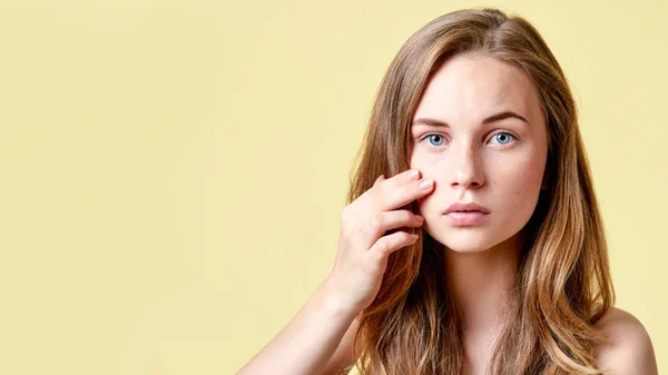 Young redhead teenager with self issues looking into mirror. Girl with low self esteem checking her skin in a mirror.