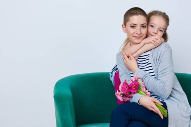 Mutlu anneler günü, kadın gün veya doğum günü arka plan. Sevimli küçük kız anne buket Pembe Gelbera vererek. Sevgi dolu bir anne ve kızı gülümseyen ve sarılma. 