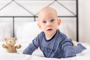 Bebek çocuk lplaying oyuncak ile bir yatak üzerinde taşımaktadır. Yeni doğan çocuk yatakta rahatlatıcı. Aile sabah evde.