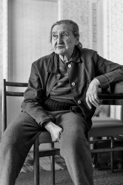 Güzel 80 artı yıl yaşlı kadın kıdemli portre. Siyah ve beyaz tam vücut görüntüsünü bir bakım evinde bir sandalyede oturan yaşlı kadın.