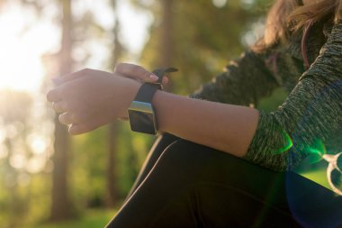 Kadın atlet üstüne egzersiz performansını izlemek için akıllı saatini koyarak. Yaşam tarzı giyilebilir teknoloji kavramı objektif parlama ile.