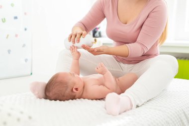 Bebek masajı geçmişi. Çocuk terapisti erkek bebeğe masaj yağı uyguluyor. Anne yeni doğmuş bebeğine masaj yapıyor..
