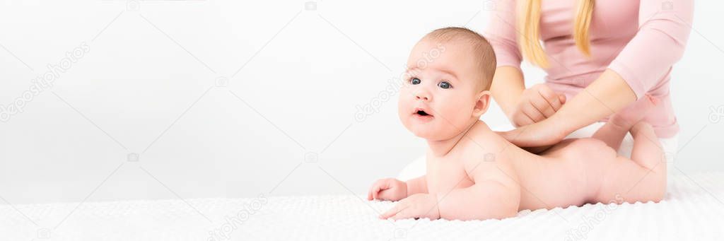 Baby massage banner. Young therapist giving a baby boy a back massage. Baby massage concept on white background with copy space.