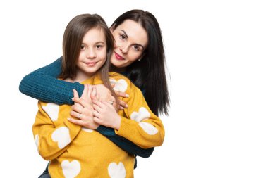 Kızını kucaklayan genç ve güzel bir annenin stüdyo portresi. Mutlu gülümseyen aile geçmişi beyaz üzerine izole edilmiş..