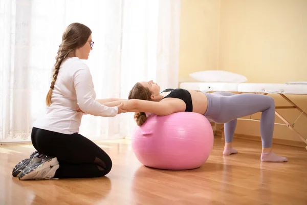 stock image Physiotherapist working with young female client on core strength using fitball. Rehabilitation and physiotherapy background.