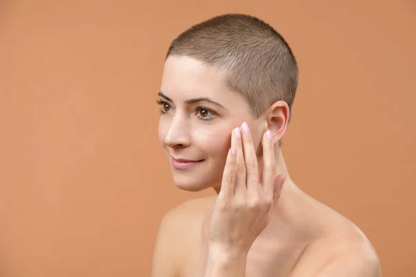 Attractive mid adult woman looking at herself in the mirror, touching her temples and pulling skin back. Photo of young woman with wrinkles isolated over brown background. Skin aging background.