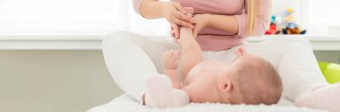 Baby massage banner with copy space. Kids therapist applying massage oil to baby boy. Mother massaging her newborn baby.