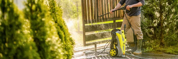 Tahta bir kapıyı elektrikli makineyle temizleyen tanınmamış bir adam. Bahçe kapısını tamir etmek için yüksek basınçlı su temizleyicisi kullanılmış. Web pankartı.