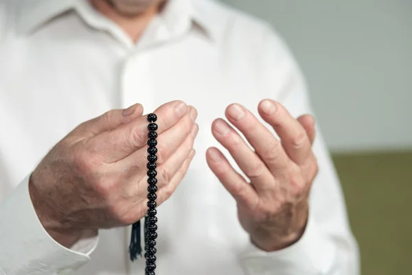 Biddende handen van een oude man met rozenkrans kralen — Stockfoto