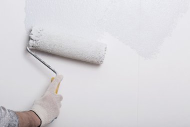 Bir duvar boya silindiri ile boyama ressam kolu yakın çekim