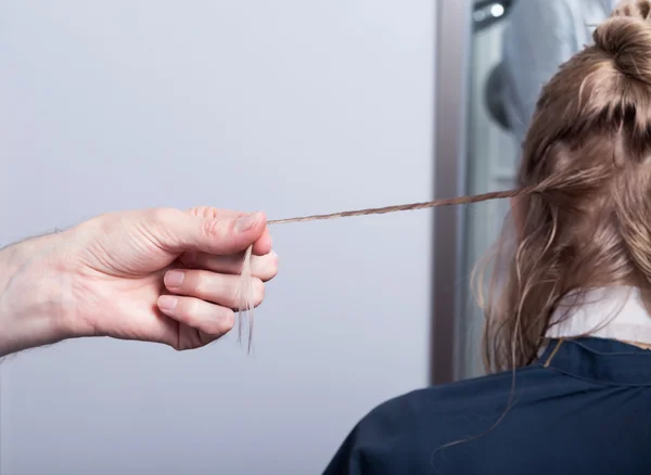 Een kapper die het maken van een kapsel voor een blond meisje — Stockfoto