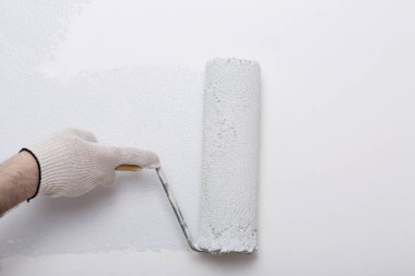 Bir duvar boya silindiri ile boyama ressam kolu yakın çekim