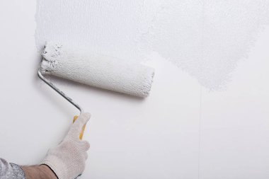 Bir duvar boya silindiri ile boyama ressam kolu yakın çekim