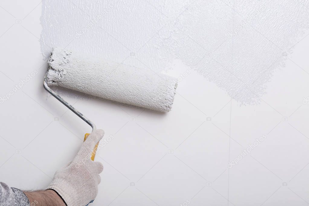 Close up of painter arm painting a wall with paint roller