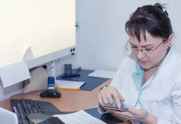 Médica feminina navegando na internet com seu smartphome — Fotografia de Stock
