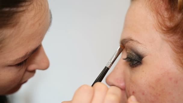 Professionele make-up kunstenaar zet cosmetica op model gezicht — Stockvideo