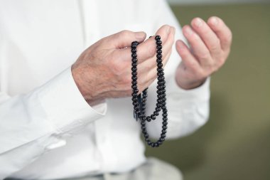 Tespih tutan bir yaşlı adamın dua eden eller