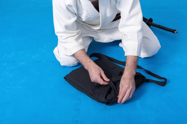 Un maestro di arti marziali con cintura nera che piega il suo hakama — Foto Stock