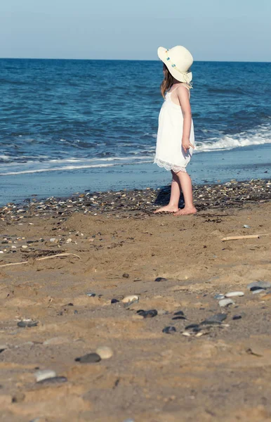 Dziewczynka w białej sukni spaceru sam morza, grając na brzegu morza — Zdjęcie stockowe