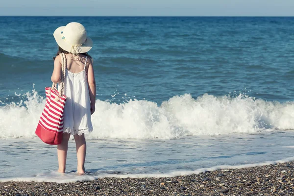 Dziewczynka w białej sukni spaceru sam morza, grając na brzegu morza — Zdjęcie stockowe