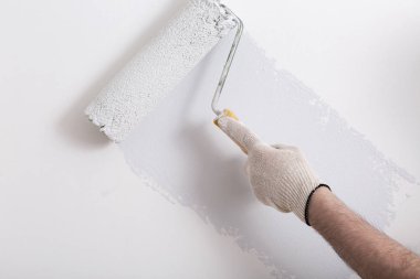 Bir duvar boya silindiri ile boyama ressam kolu yakın çekim