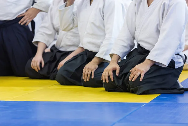 Pessoas em quimono e hakama sentadas em tatami em treinamento de artes marciais — Fotografia de Stock