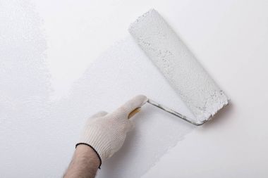 Bir duvar boya silindiri ile boyama ressam kolu yakın çekim