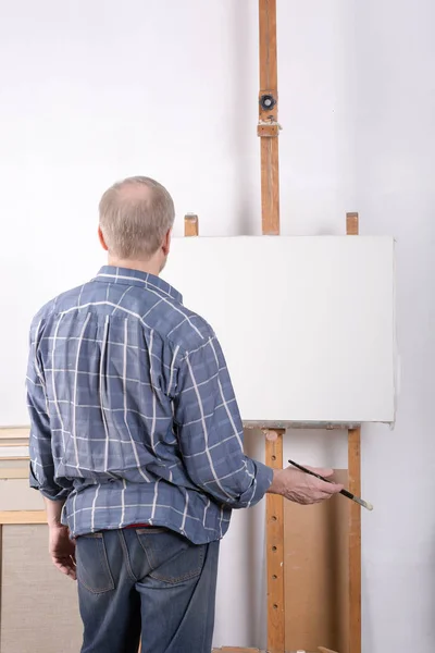 Un artiste en atelier debout devant une toile blanche — Photo