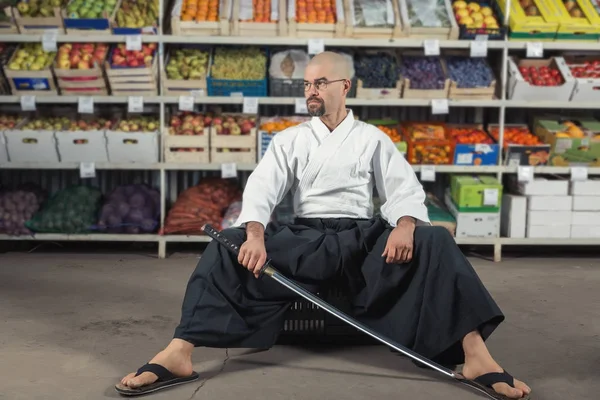 果物や野菜のラックで背景に男を着た日本の着物と袴の刀を保持. — ストック写真