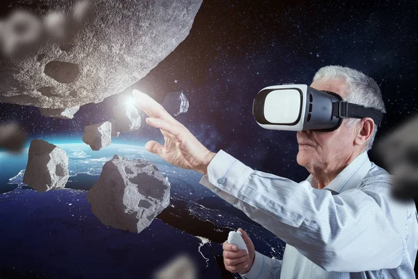 Un anciano tiene su experiencia en el espacio exterior con un auricular de realidad virtual. Elementos de esta imagen proporcionados por la NASA — Foto de Stock