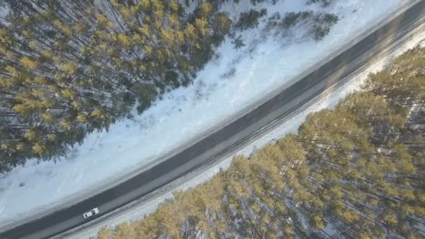 Besneeuwde weg met een rijdende auto in de winter — Stockvideo
