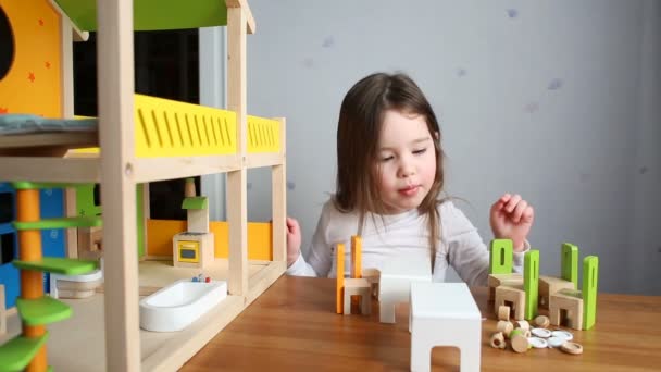 Una linda chica jugando con una casa de muñecas — Vídeos de Stock