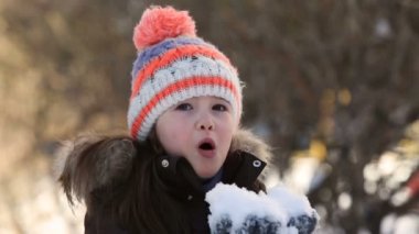 Küçük kız kışın karla oynuyor..
