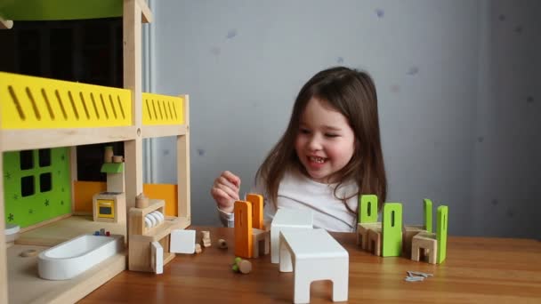 Una linda chica jugando con una casa de muñecas — Vídeos de Stock