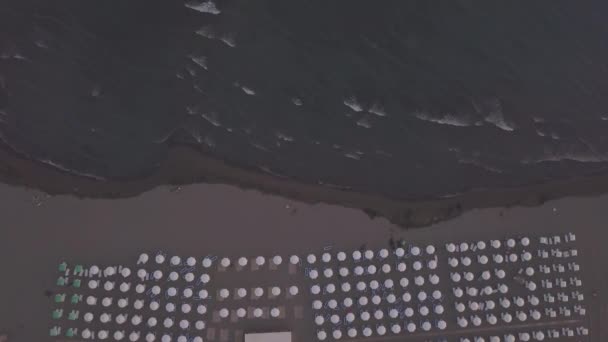 Vue aérienne de la plage de sable avec chaises longues et parasols en bois au coucher du soleil — Video